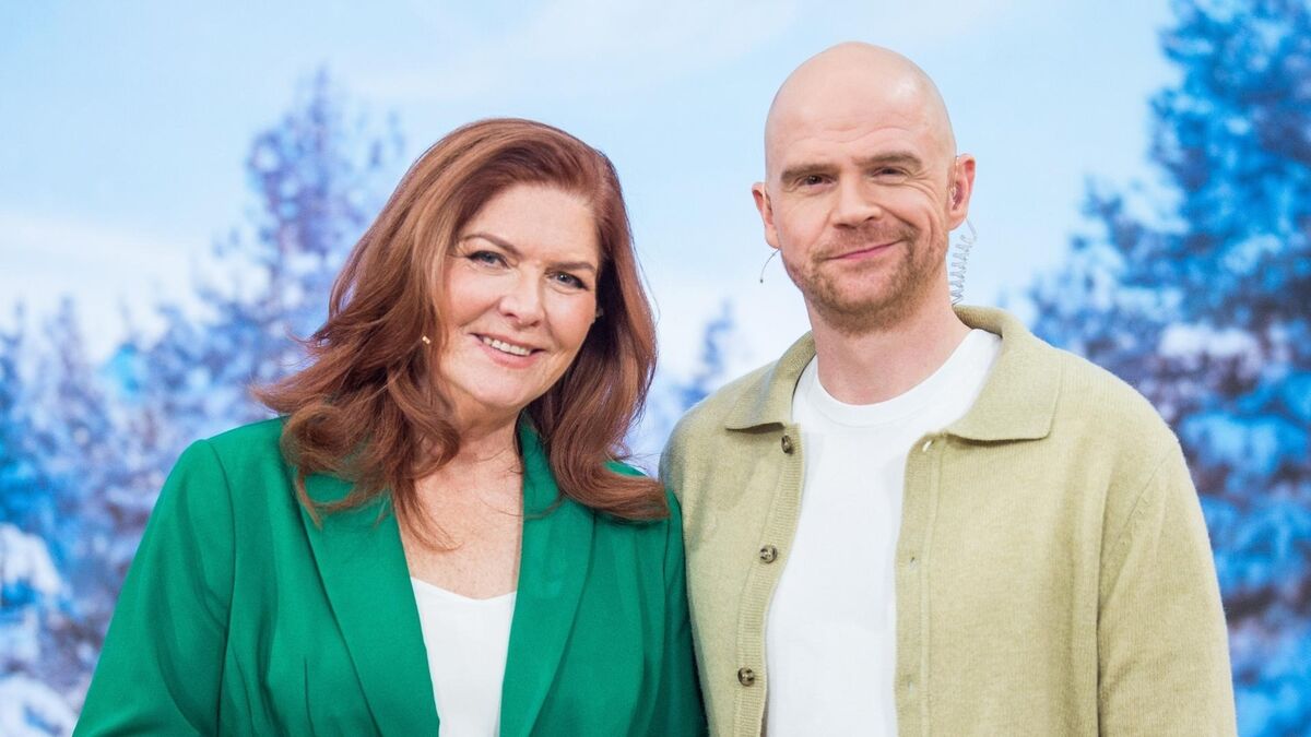 Katarzyna Dowbor i Filip Antonowicz pozują razem w studiu programu „Pytanie na śniadanie”. Ona ma na sobie zieloną marynarkę, a on jasną koszulę i beżową kurtkę, oboje mają przypięte mikrofony. W tle widoczna jest zimowa scenografia z ośnieżonymi drzewami.