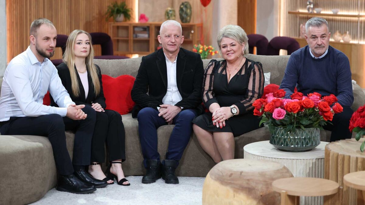 Pięć osób siedzi na kanapie w studiu telewizyjnym podczas rozmowy. Na pierwszym planie znajduje się stolik z bukietem czerwonych róż, a w tle widoczne są elementy scenografii programu.