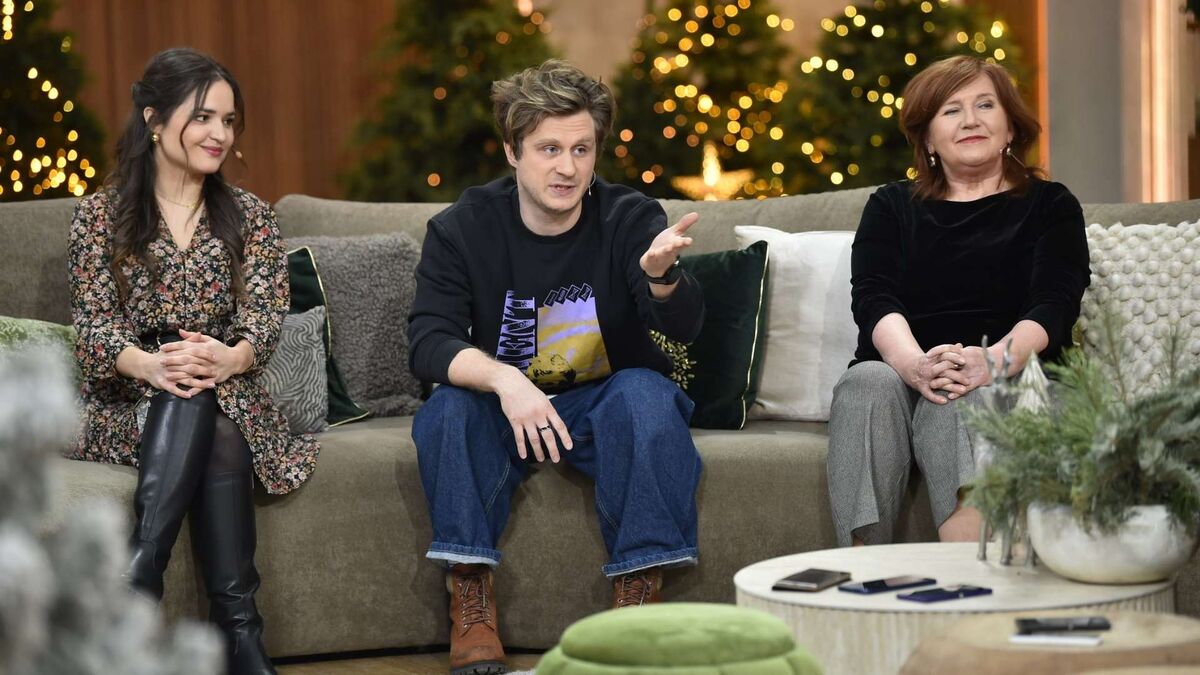 Aleksandra Radwan, Patryk Pietrzak i Ewa Ziętek siedzą na kanapie w świątecznie udekorowanym studiu programu „Pytanie na śniadanie”. Patryk Pietrzak gestykuluje podczas rozmowy, a Aleksandra Radwan i Ewa Ziętek słuchają z uśmiechem. W tle widać choinki z lampkami oraz dekoracje, które podkreślają ciepłą atmosferę programu.