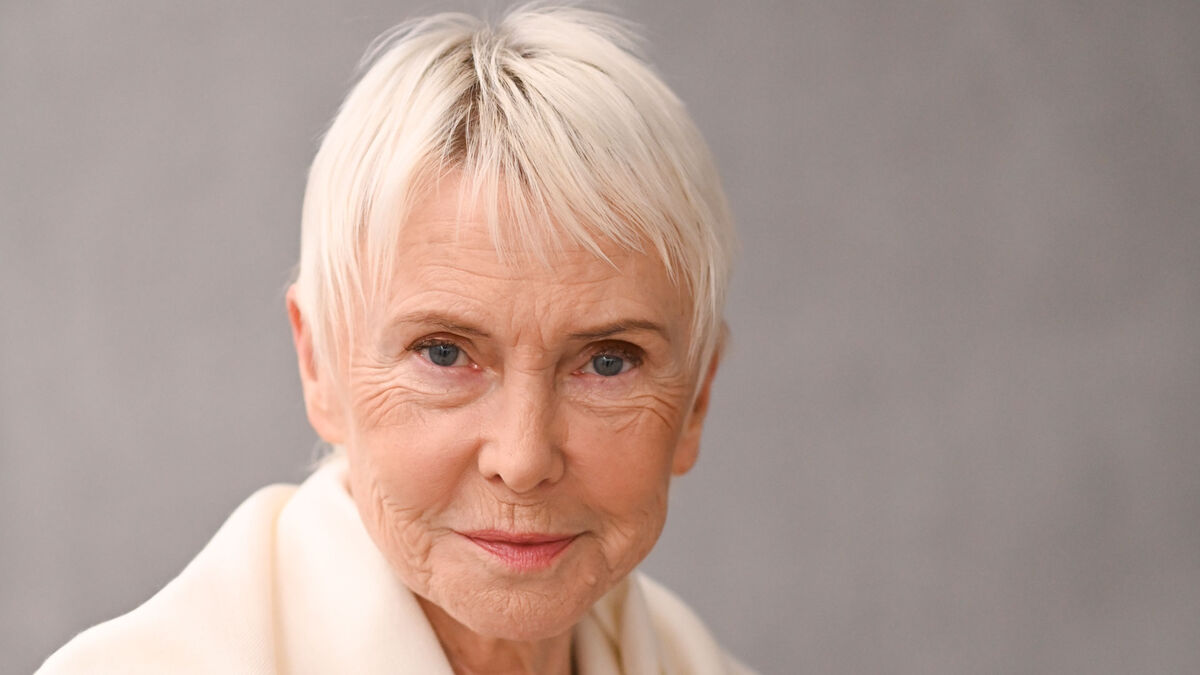 Portret Ewy Błaszczyk wykonany na neutralnym tle, z ujęciem twarzy i krótkiej fryzury. Zdjęcie przedstawia detaliczny kadr bez elementów scenografii.