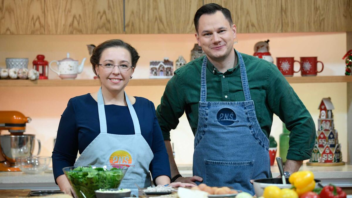 Zupa z soczewicy – przepis z „Pytania na śniadanie”. Na zdjęciu widać dwoje prowadzących w studiu kuchennym, w fartuchach z logo programu. Przed nimi znajduje się blat z produktami i naczyniami do przygotowania potrawy, m.in. warzywami i miskami.